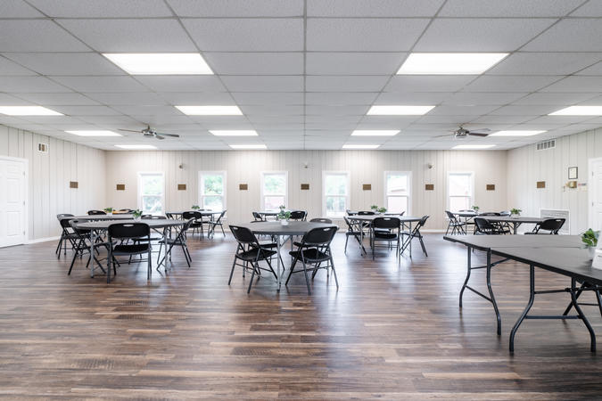 Photo of main room in the community center, containing round tables and chairs