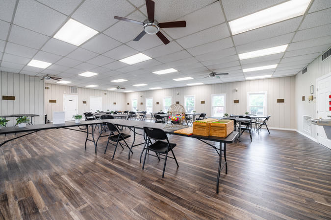 Photo of main room in community center, containing round tables and chairs