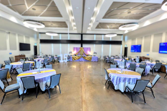Round tables draped in purple and gold, with a similarly decorated stage in preparation for a quinceanera