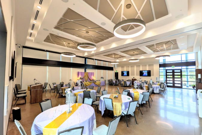 Angle of event center showing a podium, wall monitors, and artistic ceiling with large round light